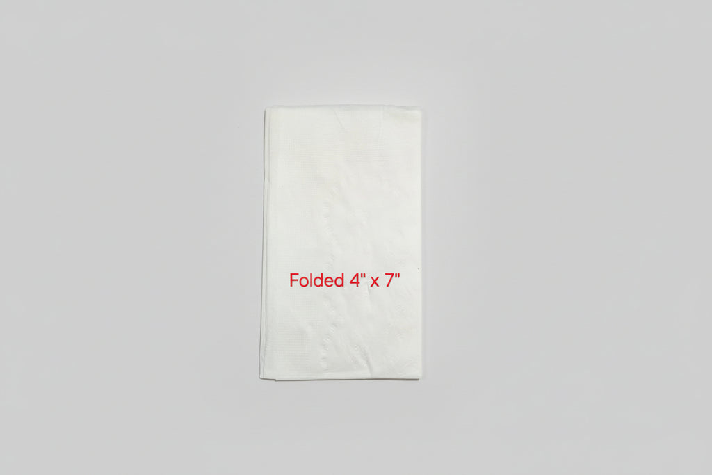 White folded paper with dimensions 4" x 7" on a brown surface with a ruler.